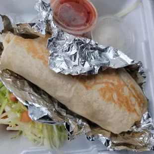 Breakfast burrito with sides of lettuce, tomato, salsa, and sour cream