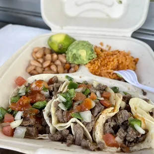 3 carne asada tacos with rice, beans, and a dollop of guac.