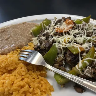 Rice, beans, asada and bell peppers with sautéed onions
