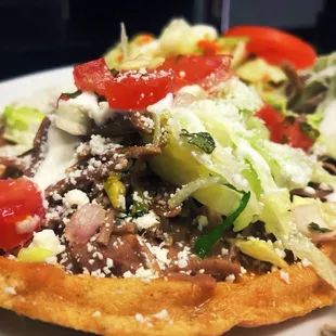 Sopes with homemade tortillas, meat, lettuce, tomatoes, sour cream, and cheese