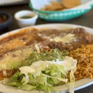 Enchilada and chile relleno combination plate with rice and beans.