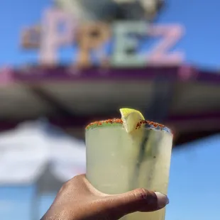 a hand holding a glass of margarita