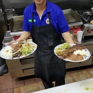 a man holding two plates of food