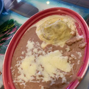 a bowl of beans and cheese on a table