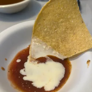 a tortilla being dipped with sauce