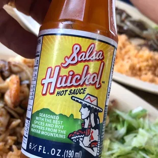 a hand holding a bottle of sauce