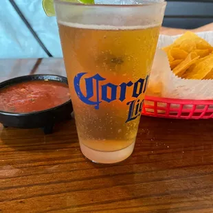 a glass of beer and a basket of chips