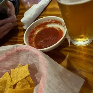 a glass of beer and a bowl of chips