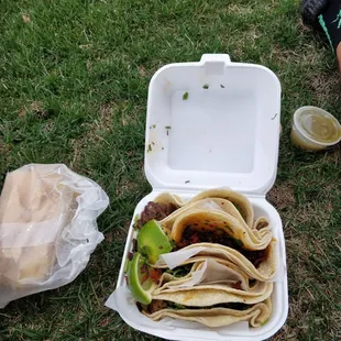 a person sitting on the grass next to a container of food