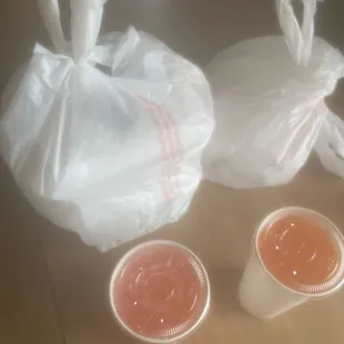 Two combination plates in the bag on the left and two burritos in the bag on the right and two drinks
