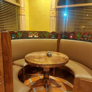 a corner booth with a table and chairs