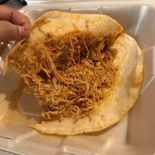 a hand holding a tortilla in a styrofoam container