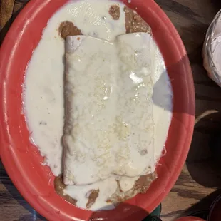 Two bean and cheese burritos with cheese sauce