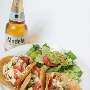 a plate of tacos and a bottle of modelo