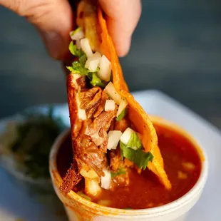 a hand dipping a tortilla