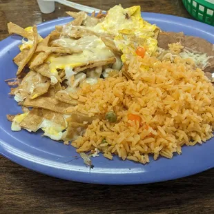 Breakfast scrambled eggs with cheese on tortilla chips with beans and rice