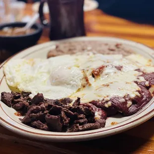 Red Chilaquiles with Beef bites and over easy eggs