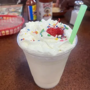 a cup of ice cream with sprinkles and a cherry
