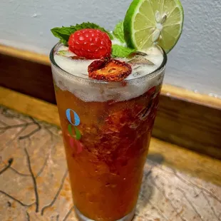 a glass of iced tea with a raspberry and lime garnish