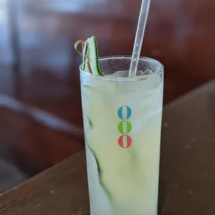 a glass of lemonade with a straw and a cucumber