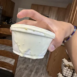 a hand holding a cup of yogurt