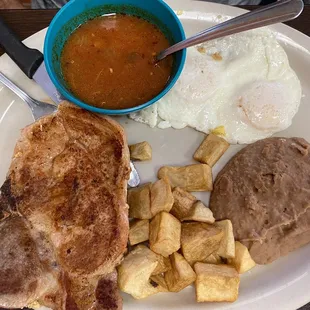 Eggs over easy with pork chop and warm salsa.