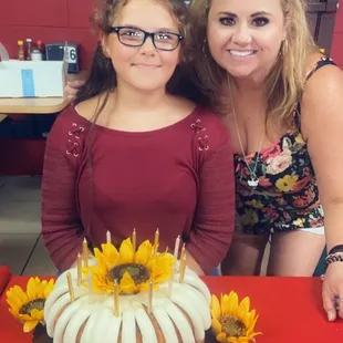 a woman and a young girl standing in front of a cake