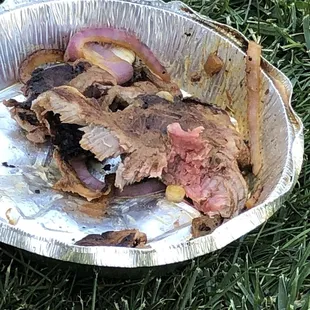 a plate of meat in a tin foil container