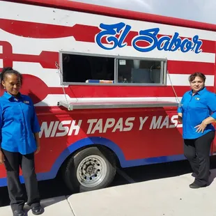 two women standing in front of a food truck