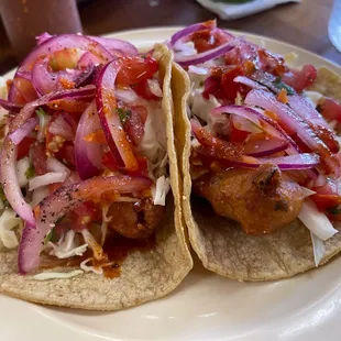 Two fish tacos with cebollitas (purple onions with lime and habanero) and their red salsa