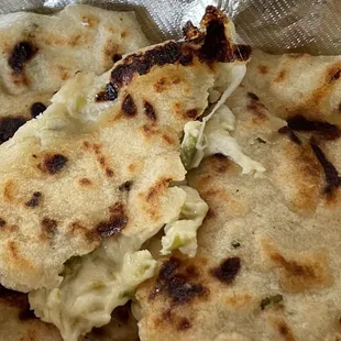 Pupusas con queso y lorocan (it&apos;s a vegetable with a light floral flavor). I ripped it open to show the pretty cheese and green lorocan.