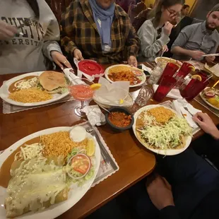 a group of people sitting at a table with plates of food