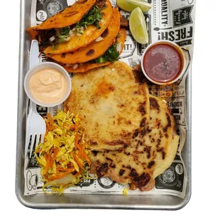 combination of quesabirrias and pupusas stuffed with pork with cheese, chipotle sauce, tomato sauce and coleslaw