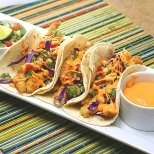 a plate of tacos and a bowl of sauce