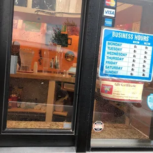 a business hours sign in a window