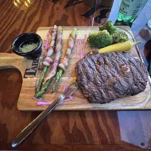 Ribeye steak cooked medium with bacon wrapped asparagus and vegetables.
