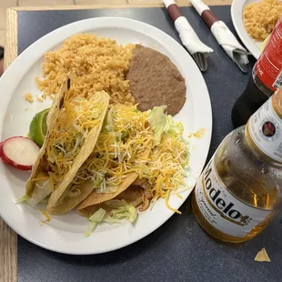 a plate of mexican food and a bottle of beer