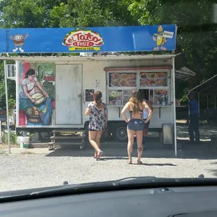 two women standing in front of a food stand