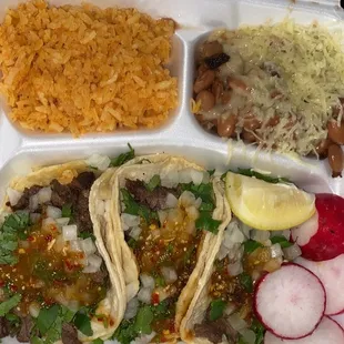 Rice, beans , cheese, tacos, asada, raddish,  lemon .