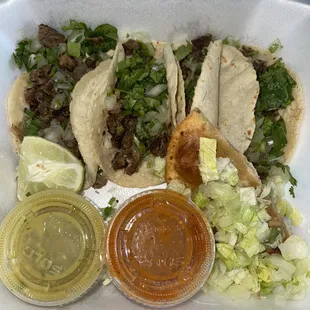 Steak tacos and a quesadilla with hot sauces