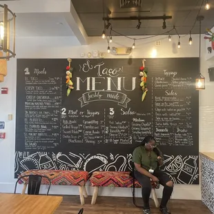 a man sitting on a bench in front of a chalkboard