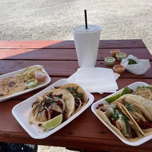 three plates of tacos and a drink