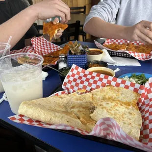 Barbacoa quesadilla (front) and two servings of birria quesadillas along with big glasses of horchata.