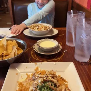 a little girl sitting at a table with plates of food