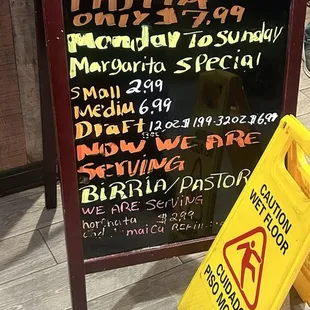 a yellow caution sign next to a blackboard