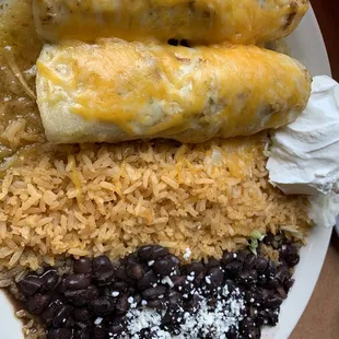 Chicken enchiladas Verdes, rice, and black beans with a dollop of sour cream.