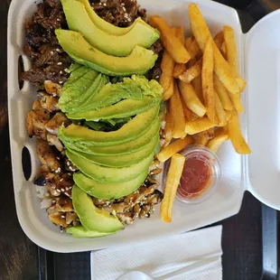 Chicken and beef plate with fries and avocado.