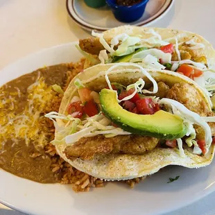 Fish taco with rice and bean plate .