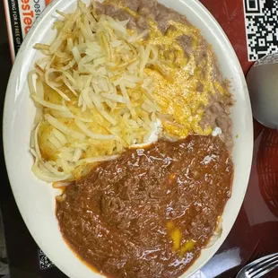 Eggs with red chili, hash browns, and refried beans.