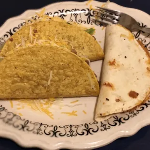 two tacos on a plate with a fork and knife